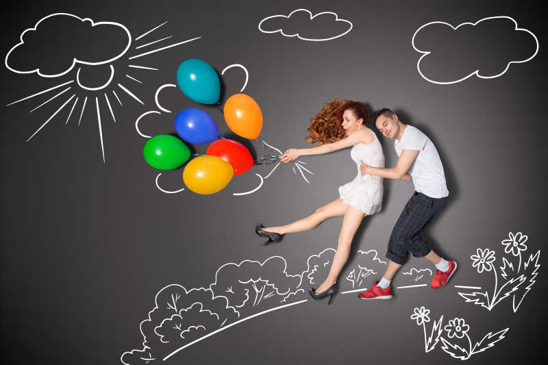 情侣两个人拉着被吹飞的气球概念特写